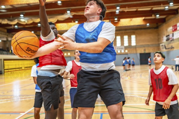 Two basketball players jumping for a rebound during a fast paced indoor court game, showcasing athleticism and competition