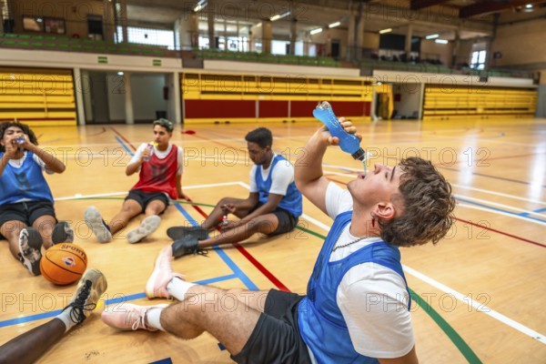 Basketball players taking a break on the court, drinking energy drinks, and recovering after an intense training session