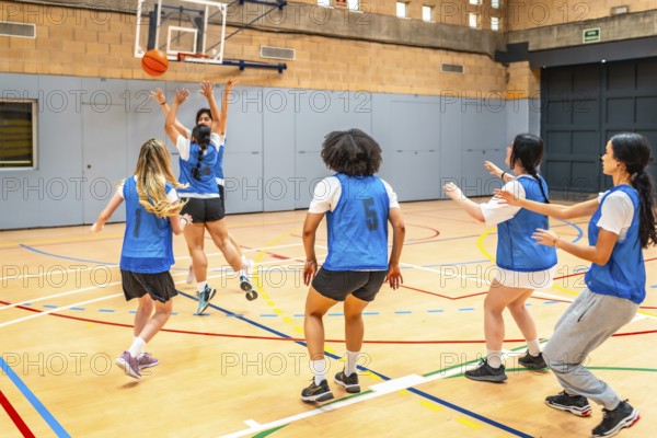 Group of young female athletes competing in a basketball match, showcasing their skills and teamwork in a vibrant sports hall environment