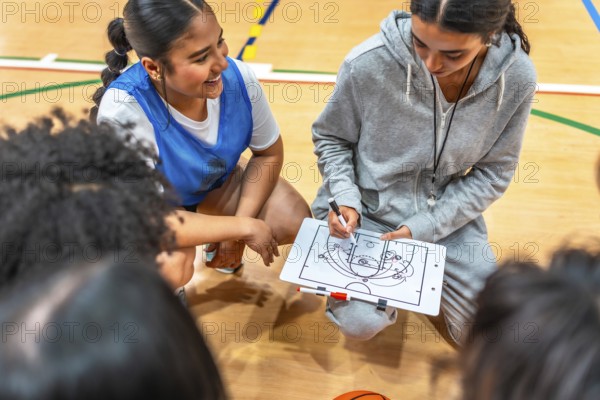 Female basketball coach drawing a play on a clipboard and explaining game strategy to her team players during a time out