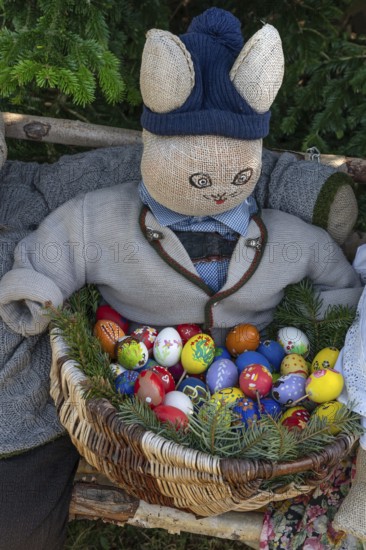 Bunny with egg basket on a bench, Easter decoration in a village in Upper Franconia, Bavaria, Germany