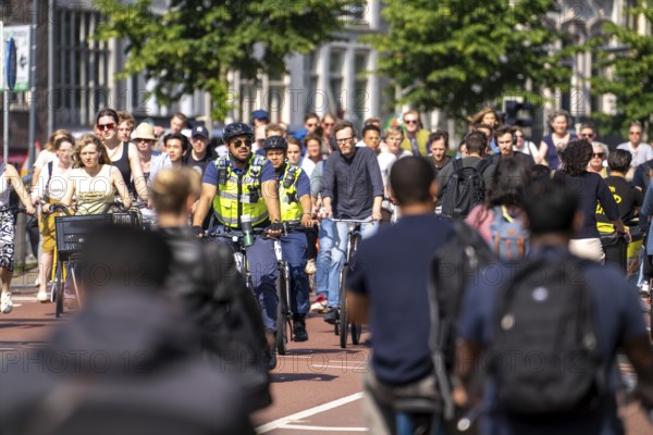 Central cycle path on the Vredenburg, in the city centre of Utrecht, lanes for pedestrians, cyclists and local traffic are separated, heavy traffic, no car/truck traffic, employees of the public order office, Toezicht en handhaving, on cycle patrol, Utrecht, Netherlands
