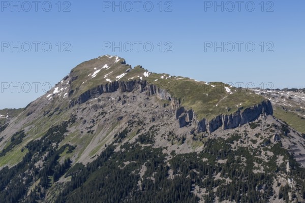 The rocky mountain peak Hohe Ifen and the Gottesacker plateau with snow and grass under a clear blue sky in Kleinwalsertal, Austria