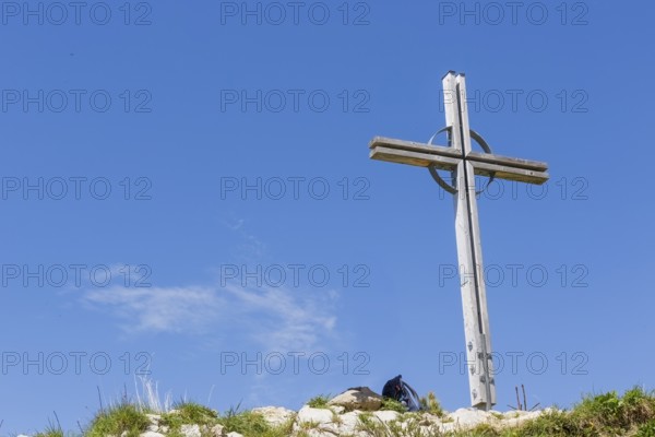 Summit cross of the Kuhgehrenspitze in Mittelberg rises in front of a bright blue sky in Kleinwalstertal, Mittelberg, Kleinwalsertal, Austria