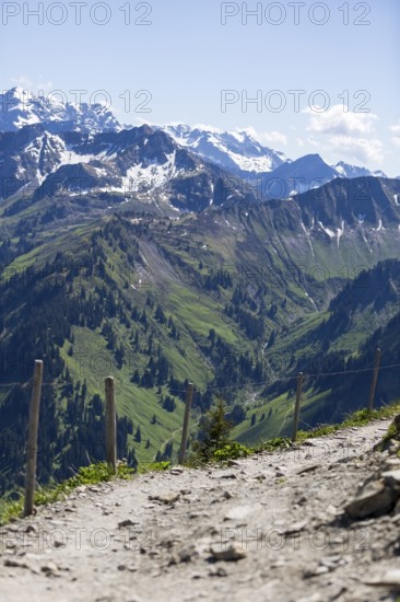 View of mountain landscape with hiking trail and snow-covered Alpine peaks