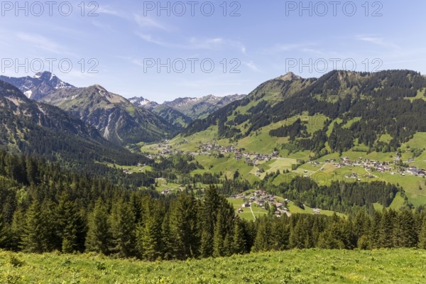 Sweeping views of the mountain village of Mittelberg nestled in lush greenery in Kleinwalsertal, Austria
