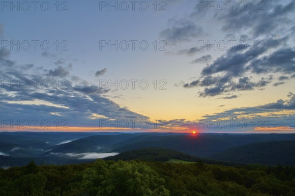 Sunrise over a forest landscape with vivid sky and clouds, warm colours of the morning, Katzenbuckel, Waldbrunn, Neckar-Odenwald-Kreis, Odenwald, Baden-Württemberg, Germany