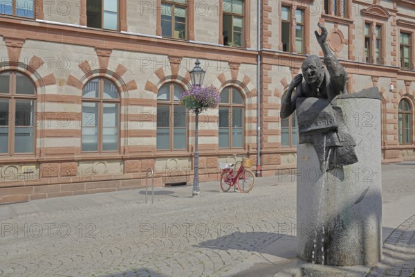Historic post office and post office fountain with sculpture symbolising silent mail, telephone, fountain, cyclist, Bernburg, Saxony-Anhalt, Germany