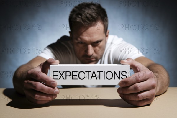 Man holding block labeled expectations, symbolizing social pressure and masculine burden. Generative AI, AI generated