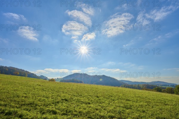 Wide meadow landscape under a bright sun and blue sky, Vöckelsbach, Mörlenbach, Bergstrasse district, Odenwald, Hesse, Germany