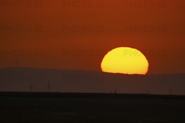 The sun rises behind the Winterstein (left) in the Wetterau, Frankfurt am Main, Hesse, Germany