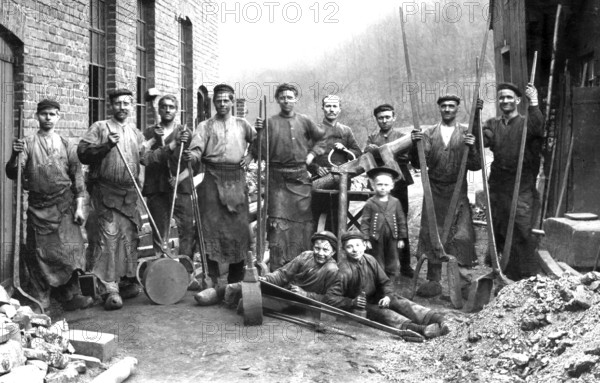 Construction worker, child labour, ca. 1910, group of workers in historical clothing in front of a brick wall with tools, historical photo