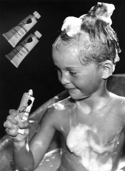 Child washing hair with shampoo, 1930, A child with shampoo in his hair and soap on his body holds a tube in his hand, Historical photo
