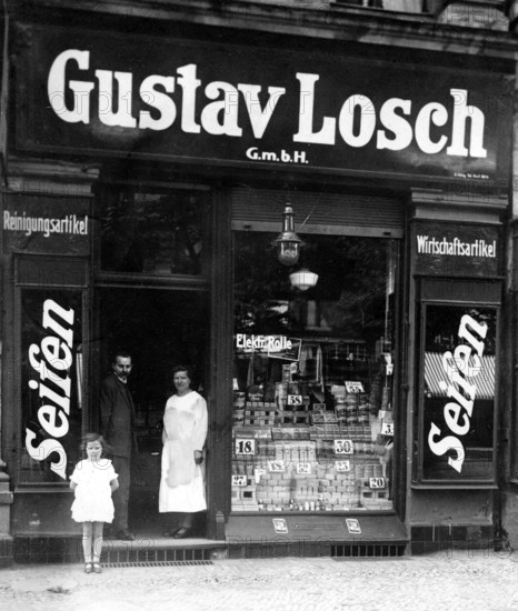 Soap shop, 1910, A man, a woman and a child stand in front of an old soap shop with a large sign outside, historical photo