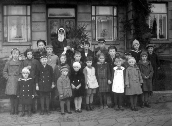 Group of children Father Christmas, 1930, Group of children with a disguised Father Christmas in front of a house, historical photo