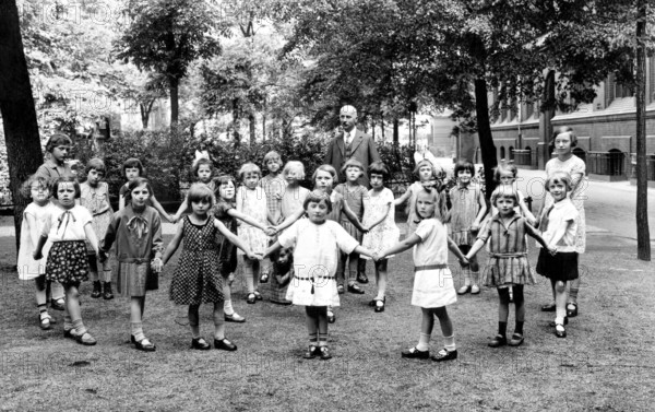 School class break Ringelreihen teacher, ca. 1920, Group of children with a teacher in the park holding hands, historical photo