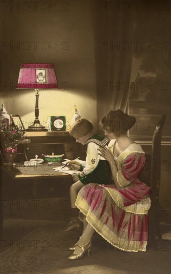 1910, Mother with child practising writing, child and mother at a desk in dim lamp light, historical photo