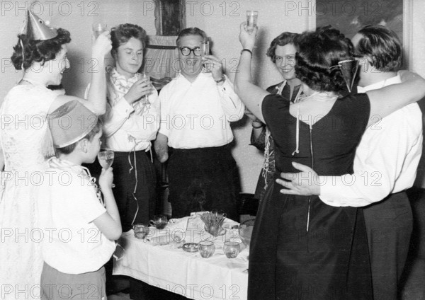 New Year's Eve champagne toast, 1940, adults celebrating together with raised glasses in a joyful atmosphere, historical photo
