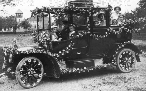 Wedding car with flowers, 1910s, A happy family sits outside in a vintage car decorated with flowers, Historical photo
