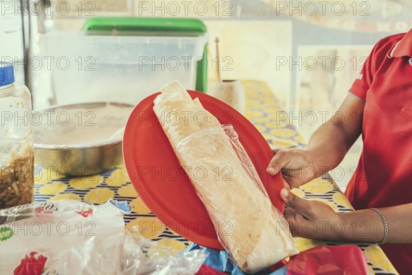 Hands of a person serving traditional quesillo. Vendor serving delicious quesillo in a bag