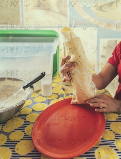 Vendor serving delicious quesillo in a bag. Hands of a person serving traditional quesillo