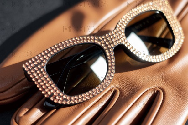 Rhinestone sunglasses resting on leather glove. A symbol of luxury, glamour, and timeless elegance. Generative ai, AI generated