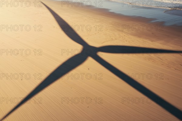 Wind turbine shadow on sunlit beach. A poetic symbol of clean energy blending with nature. generative ai, AI generated
