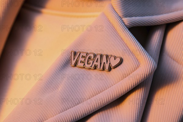 Close-up of pin with text Vegan and heart on pastel cotton jacket. A symbol of ethical living and compassionate choice. Generative Ai, AI generated