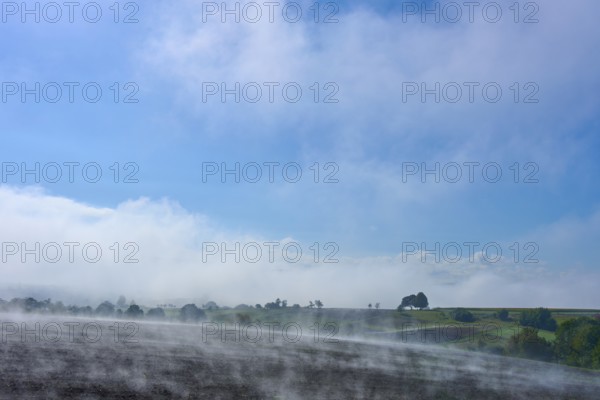 A wide landscape with fog, blue sky and trees in the distance, Schmachtenberg, Miltenberg, Spessart, Bavaria, Germany