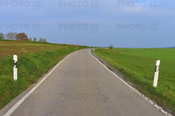 Lonely country road through green fields under a cloudy sky, Hornbach, Walldürn, Odenwald, Neckar-Odenwald Kreis, Baden-Württemberg, Germany