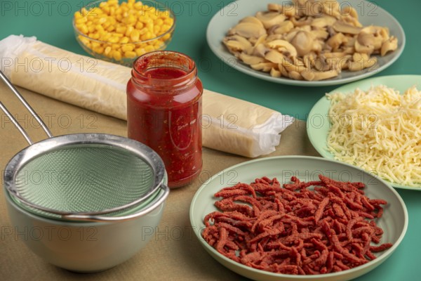 Ingredients for preparing a pizza arranged on a green table