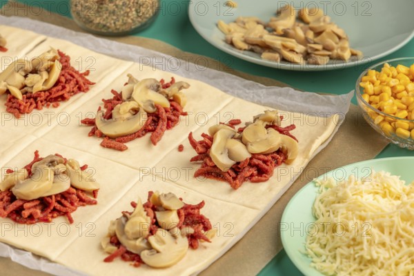 Sliced dough squares with tomato paste, bacon and mushrooms alongside other ingredients for pizza, balls