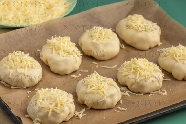 Raw pizza, balls with grated cheese on baking paper, ready for the oven