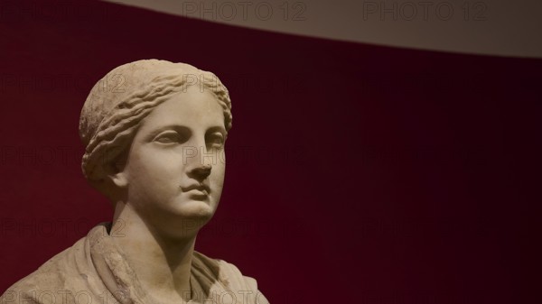 Ancient bust of a woman against a red background, showing classical stone carving, Archaeological Museum, Kos Town, Kos, Dodecanese, Greek Islands, Greece