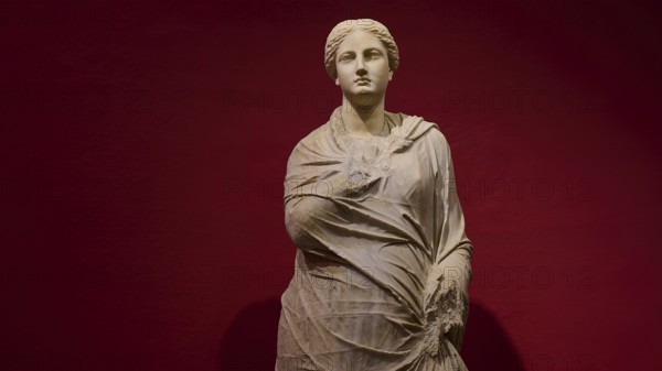 Marble statue of a woman in draped shawls, depicted against a red background, Archaeological Museum, Kos Town, Kos, Dodecanese, Greek Islands, Greece