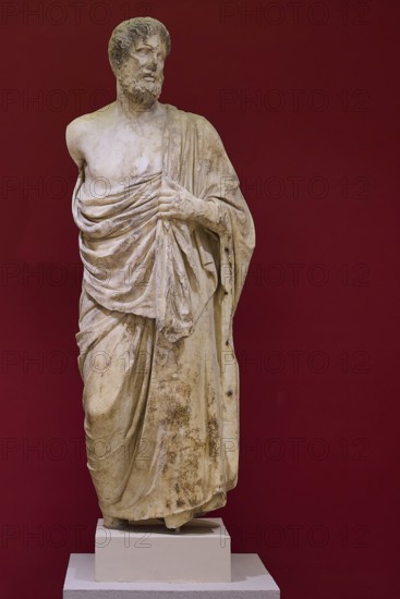 Marble statue of a bearded man in classical pose, surrounded by cloths, Archaeological Museum, Kos Town, Kos, Dodecanese, Greek Islands, Greece