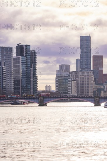 Modern cityscape with skyscrapers and a bridge across a river at sunset, London, United Kingdom, World