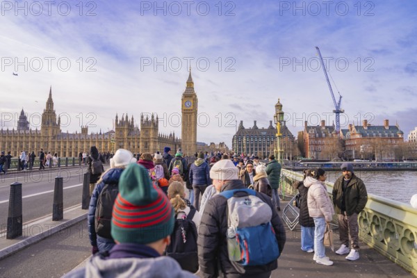 Tourists on a bridge looking at a famous clock tower on a clear day, London, United Kingdom, World