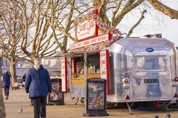Silver food truck in a park surrounded by bare trees and pedestrians, London, United Kingdom, World