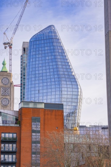 Modern building with glass façade and construction crane under blue sky, London, United Kingdom, World
