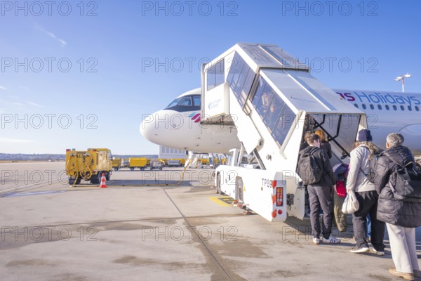 People board an airplane via a gangway, clear blue sky in the background, London, United Kingdom, World