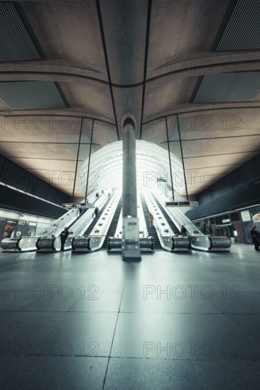 Bright, symmetrical escalator system in a modern station concourse, Canary Wharf Station, London, United Kingdom