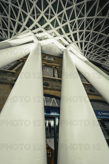 Dramatic perspective of huge white pillars under a modern glass roof, King's Cross Station, London, United Kingdom, World