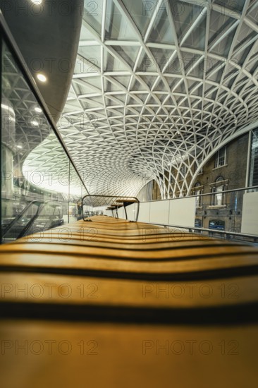 View along a bench under an expansive, modern glass roof in the train station, King's Cross Station, London, United Kingdom, World
