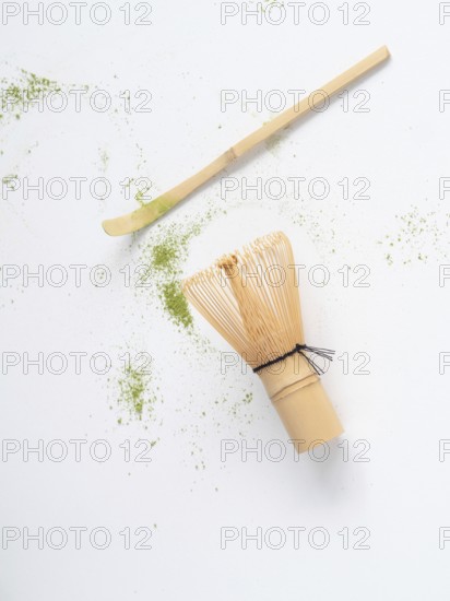 Matcha tea ceremony tools with scattered green powder on white background