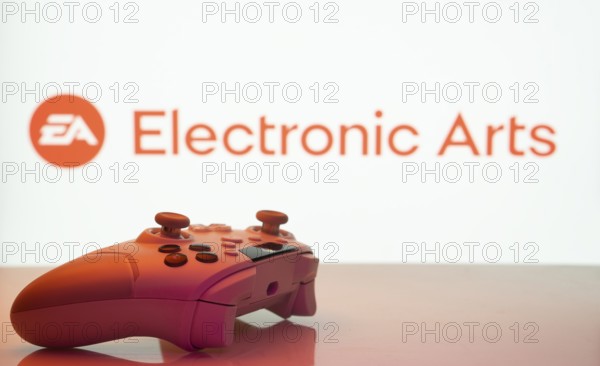 Dhaka, Bangladesh- 20 Mar 2025: A close-up of a white gamepad with the Electronic Arts seen on screen in the background