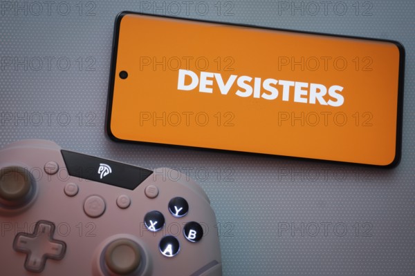 Dhaka, Bangladesh- 22 March 2025: Devsisters logo displayed on a smartphone surrounded by gaming accessories in an Blue background