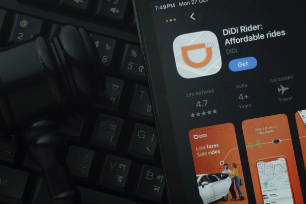 Dhaka, Bangladesh- 28 Oct 2025: An iPad displaying the DiDi Rider app against a judge's gavel and dark keyboard background