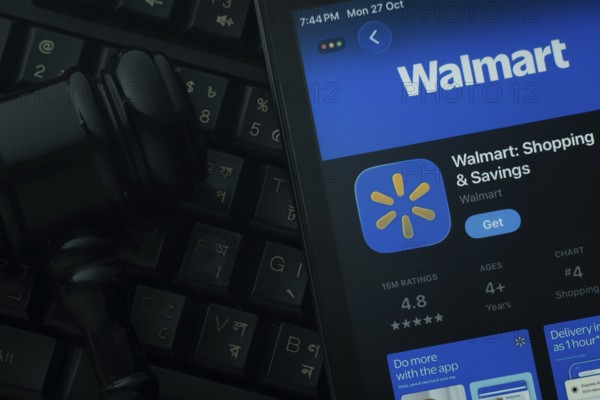 Dhaka, Bangladesh- 28 Oct 2025: An iPad displaying the Walmart app against a judge's gavel and dark keyboard background