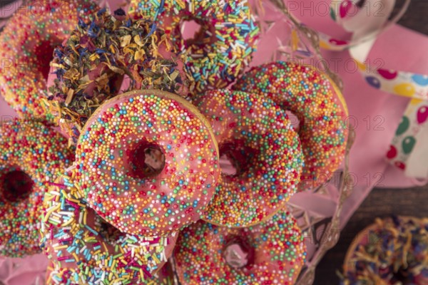 Colourful donuts with sprinkles and streamers on pink cloth, carnival